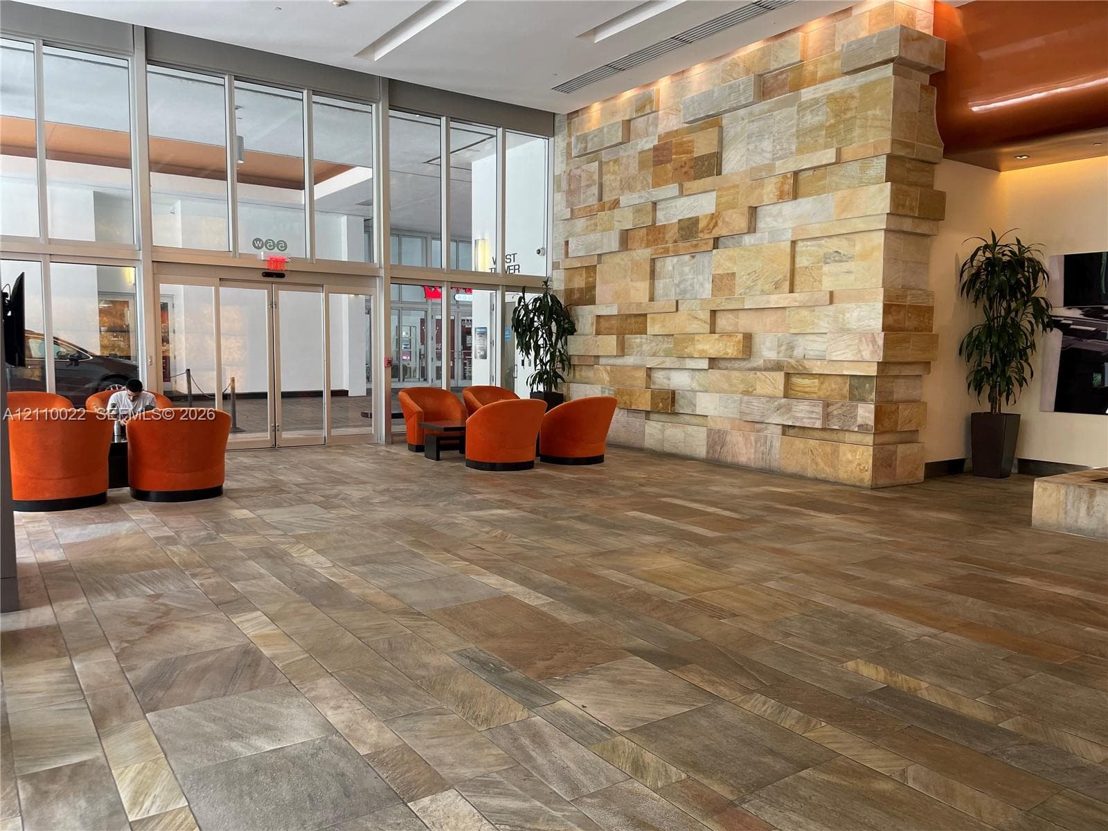 Lobby featuring multi-tonal stone flooring, floor-to-ceiling glass paneling, and an expansive dimensional stone accent wall