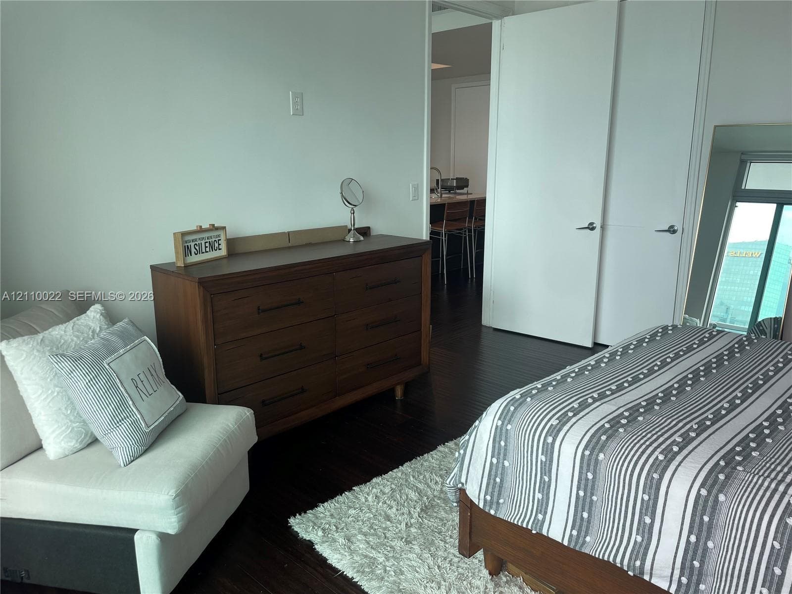 Dark wood-finish flooring, white walls, and dual-panel closet doors with satin-finish hardware