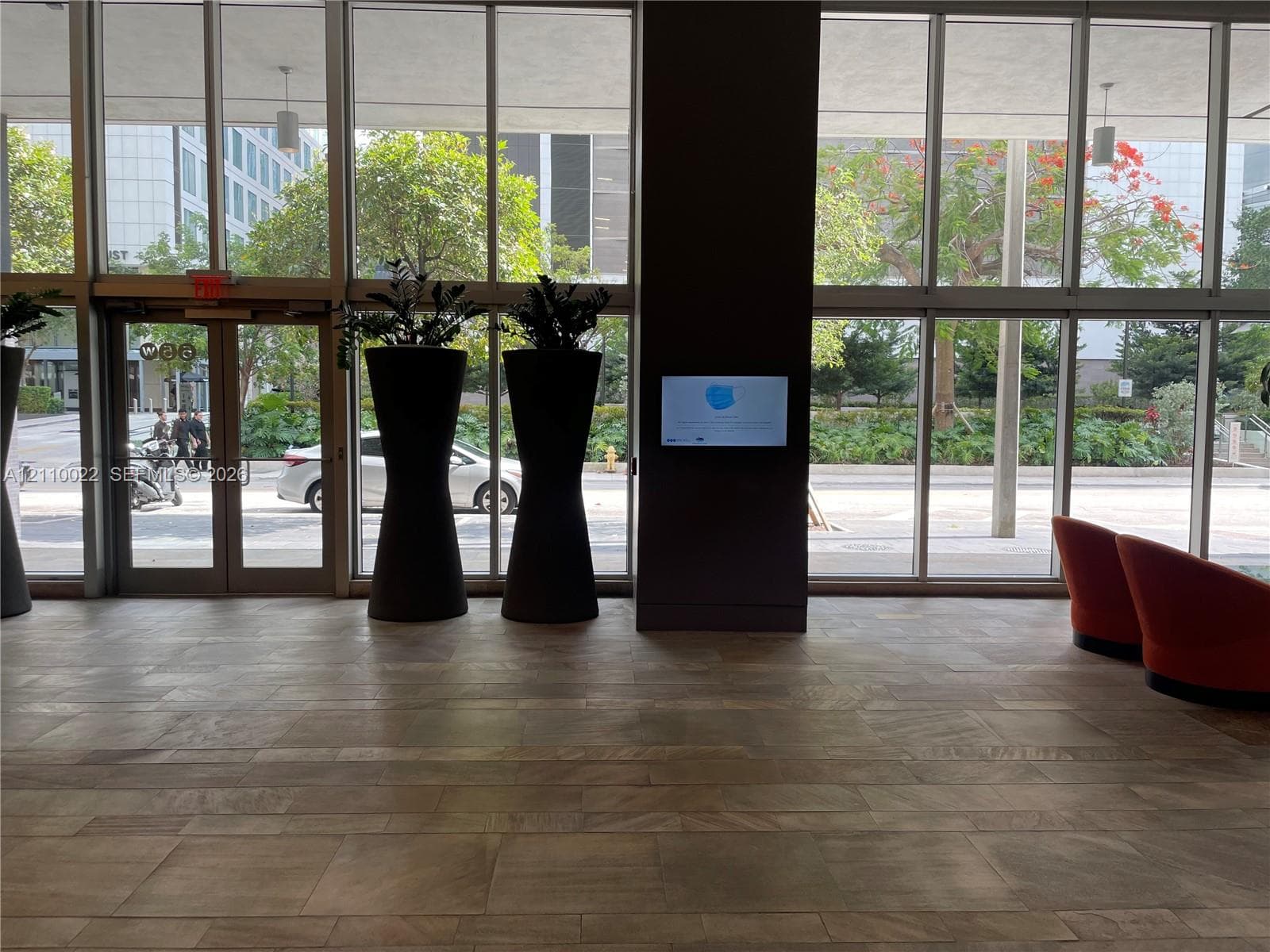 Floor-to-ceiling glass windows, neutral stone-finish flooring, and recessed ceiling lighting