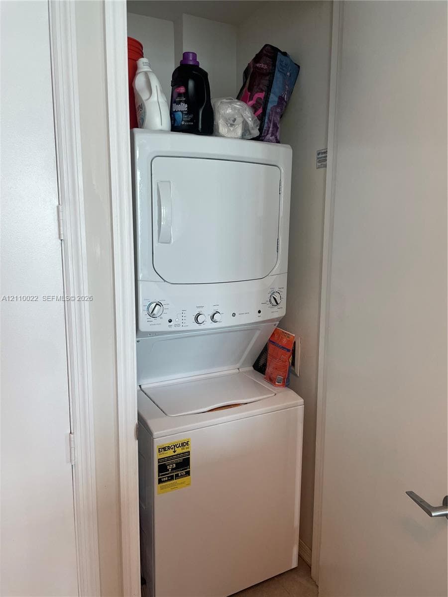 Stacked laundry center featuring a white top-load washer and matching dryer housed within a dedicated closet