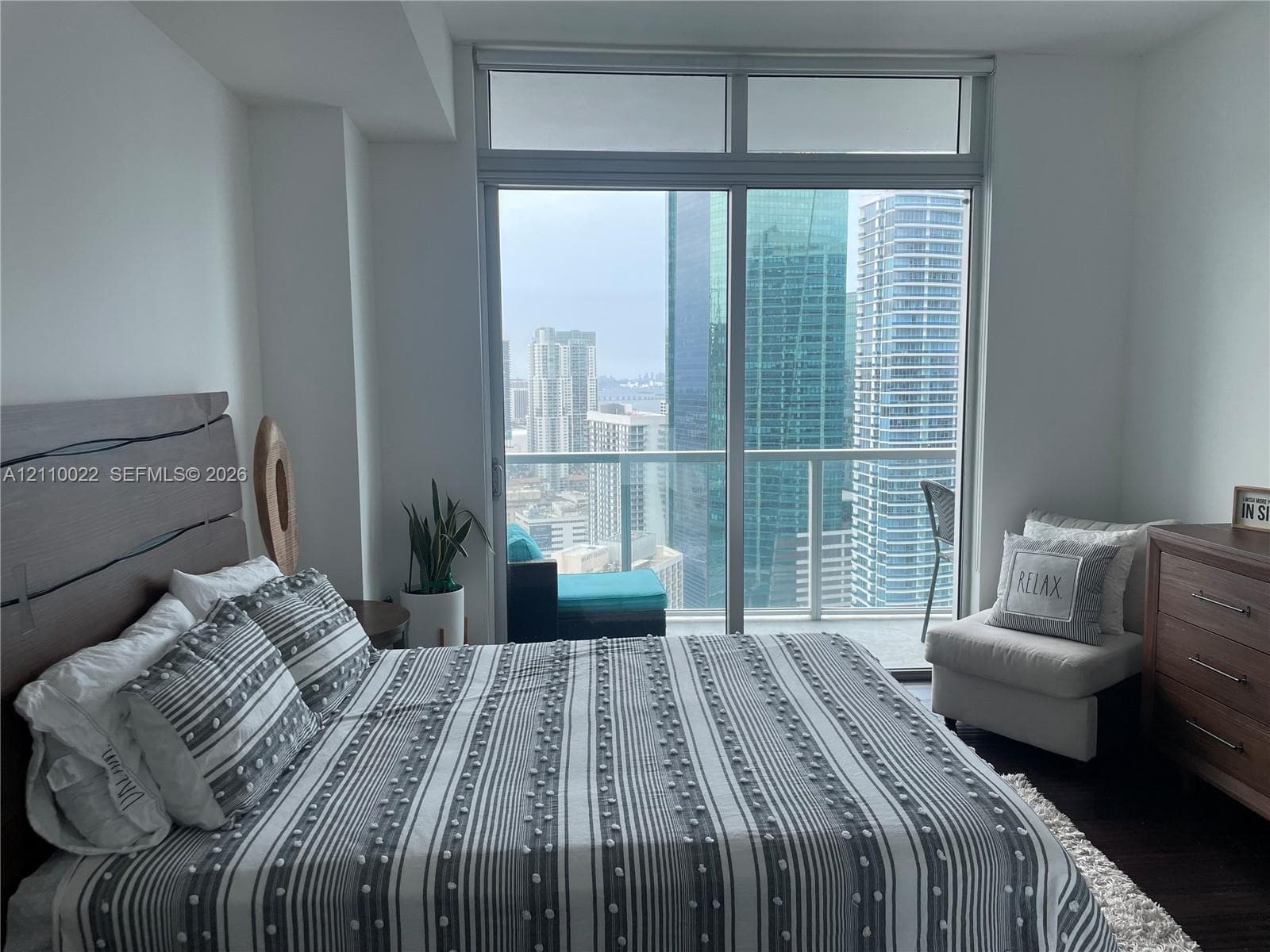 Floor-to-ceiling sliding glass door, glass-panel balcony railing, and expansive window configuration with urban skyline scenery