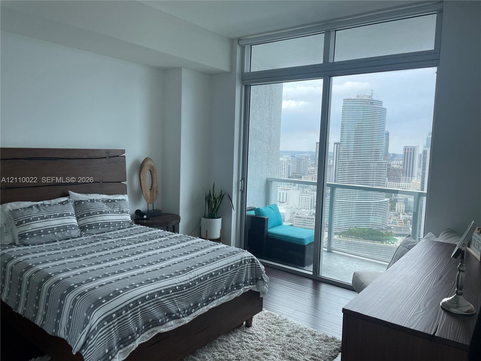 Floor-to-ceiling windows, private balcony, wood-finish flooring, and neutral wall tones