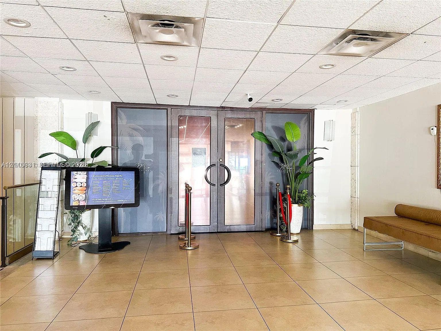 Lobby entrance featuring large glass-paneled double doors, recessed ceiling lighting, and tile flooring