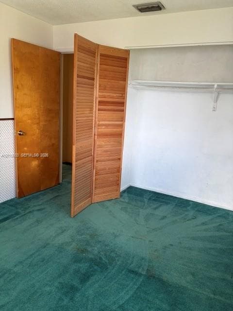 Interior space featuring wall-to-wall carpeting, wood-finish bi-fold louvered closet doors, and a solid wood interior door
