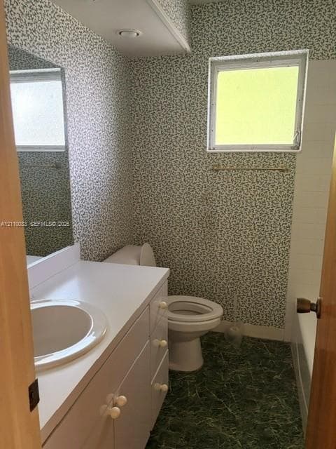 Bathroom featuring a white vanity cabinet with a solid-surface countertop and integrated sink, a large wall-mounted mirror, and a built-in bathtub with a shower surround