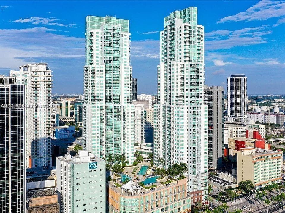 High-rise residential towers featuring glass-facade architecture, private balconies, and an elevated podium terrace with a swimming pool