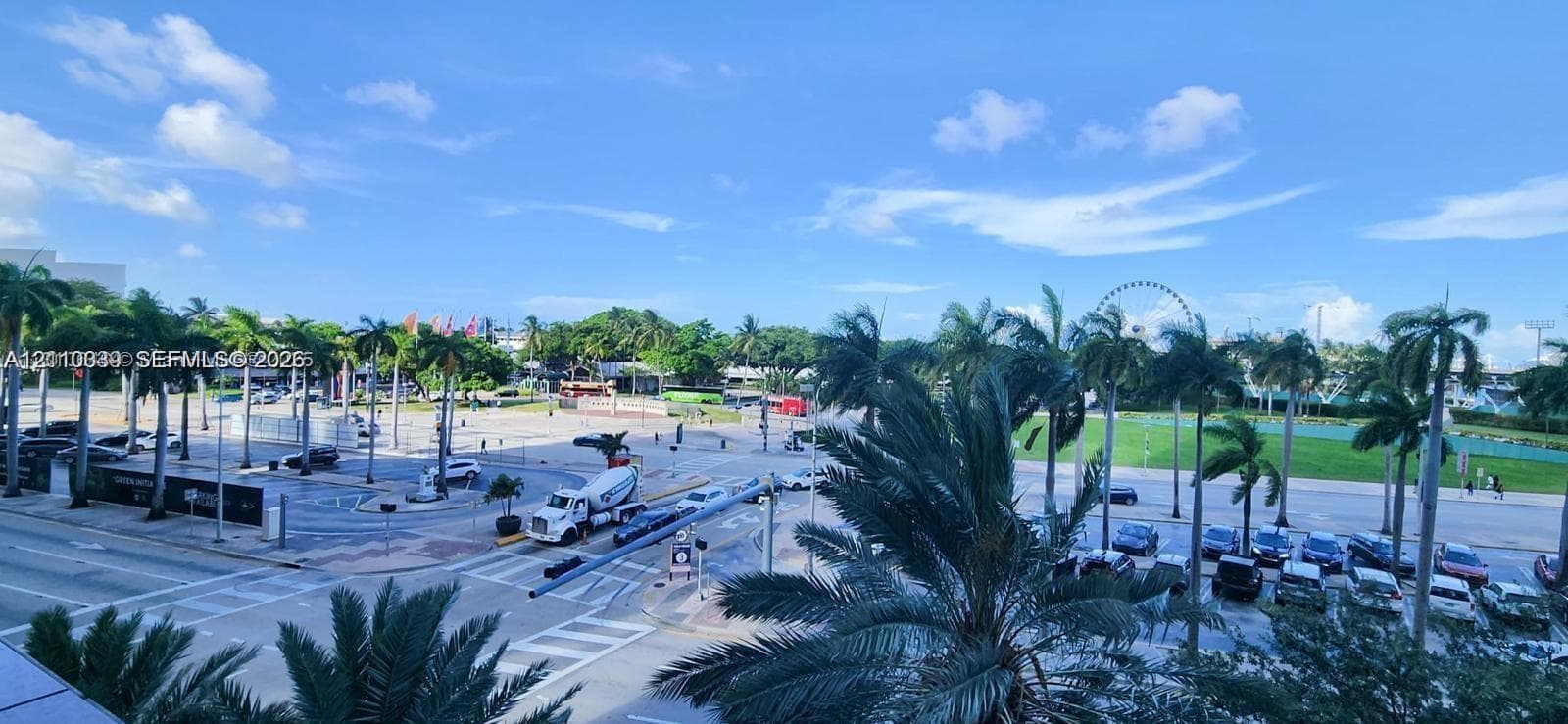 Elevated exterior perspective featuring mature palm trees, paved parking areas, and expansive open green space