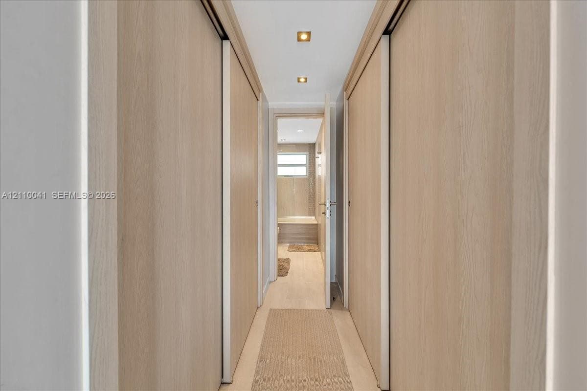 Hallway featuring floor-to-ceiling wood-finish sliding doors, recessed lighting, and wood-finish flooring