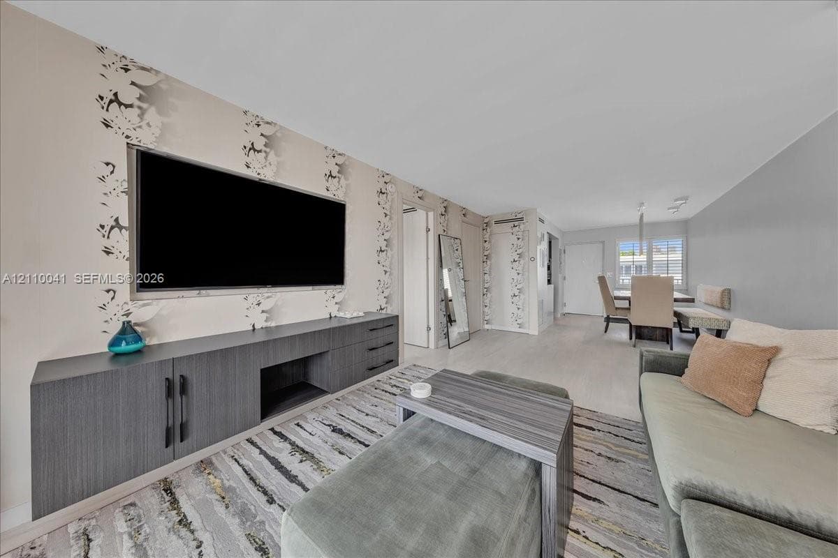 Living area featuring custom charcoal-finish built-in cabinetry, patterned wallpaper, light-toned flooring, and recessed lighting