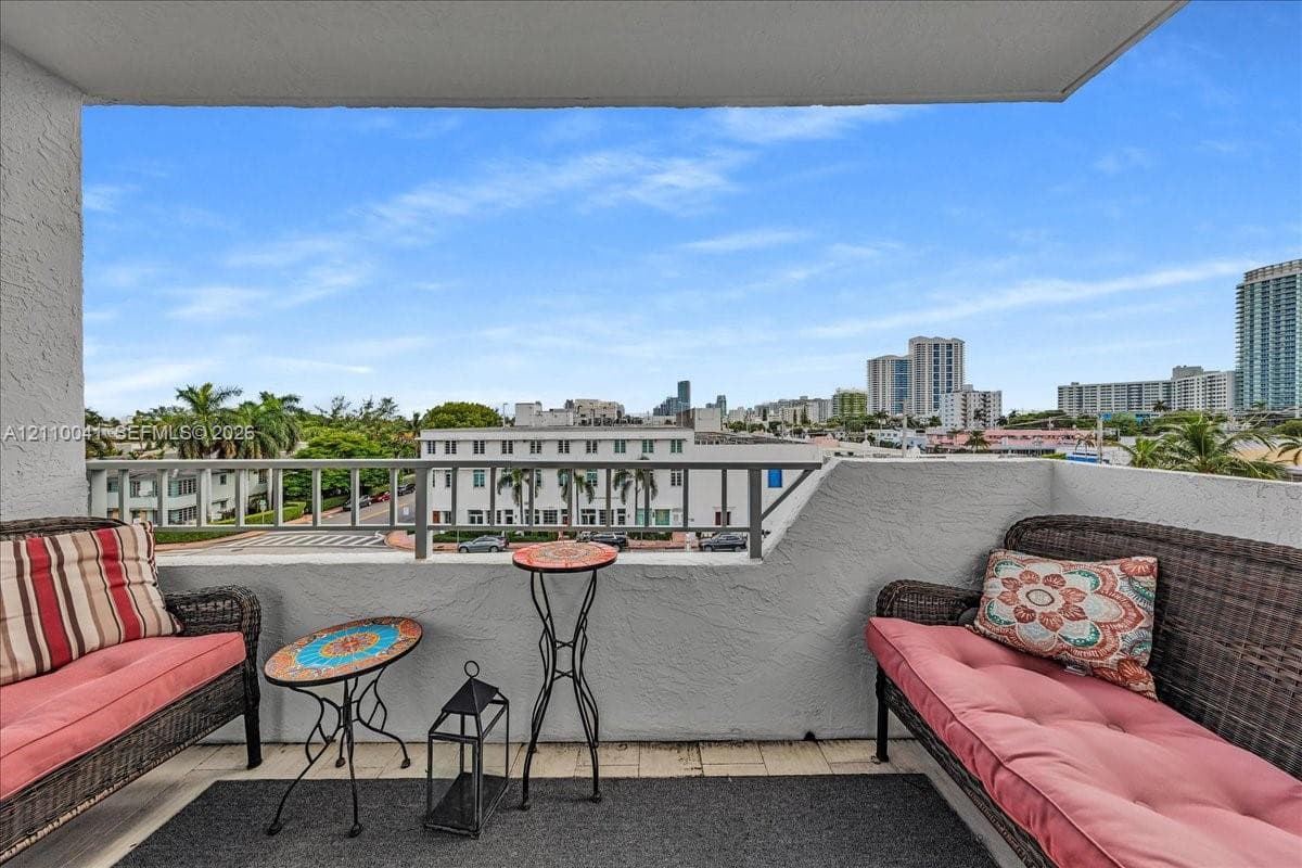 Covered balcony featuring textured stucco walls, tiled flooring, and a metal railing