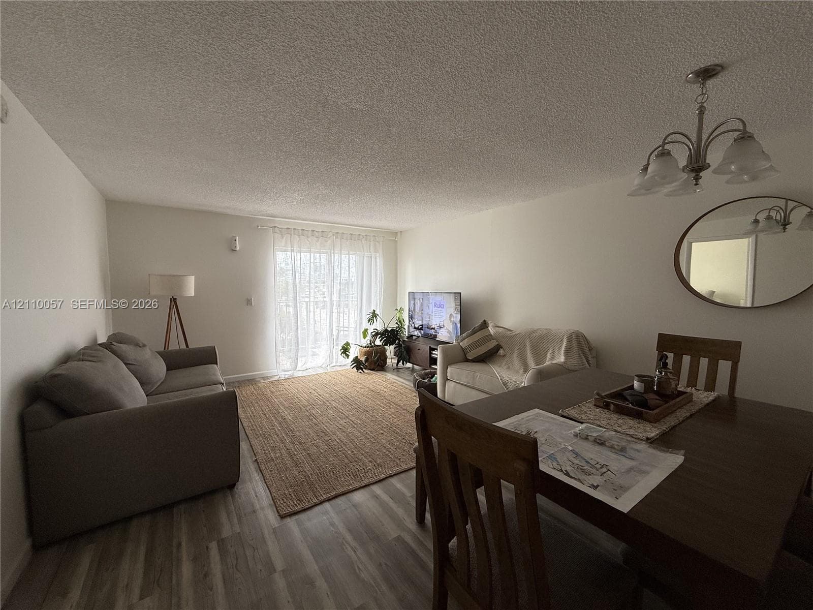Living area featuring wood-finish flooring, sliding glass doors, and a multi-light chandelier