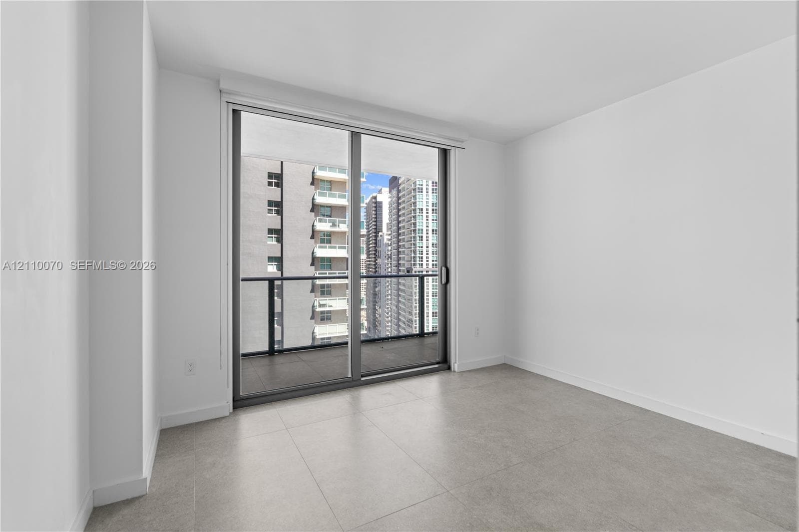 Large-format tile flooring, expansive sliding glass door, and private balcony with metal railing