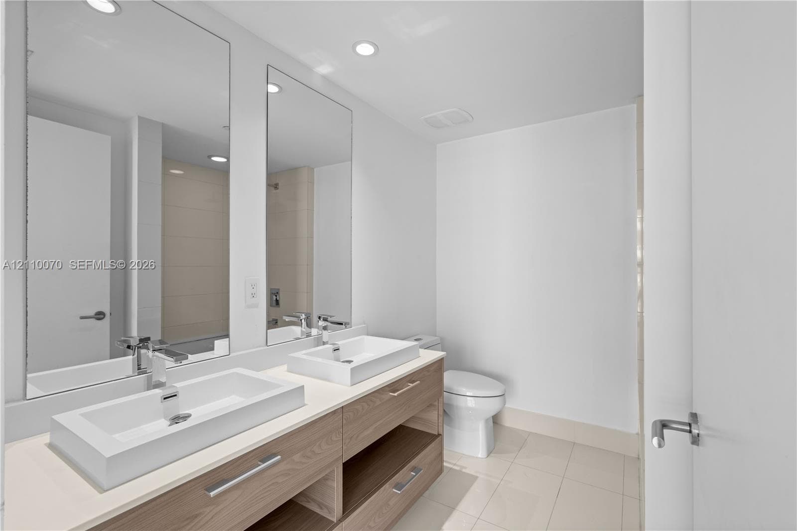 Double floating vanity featuring wood-finish cabinetry, rectangular vessel sinks, polished chrome hardware, and oversized wall-mounted mirrors