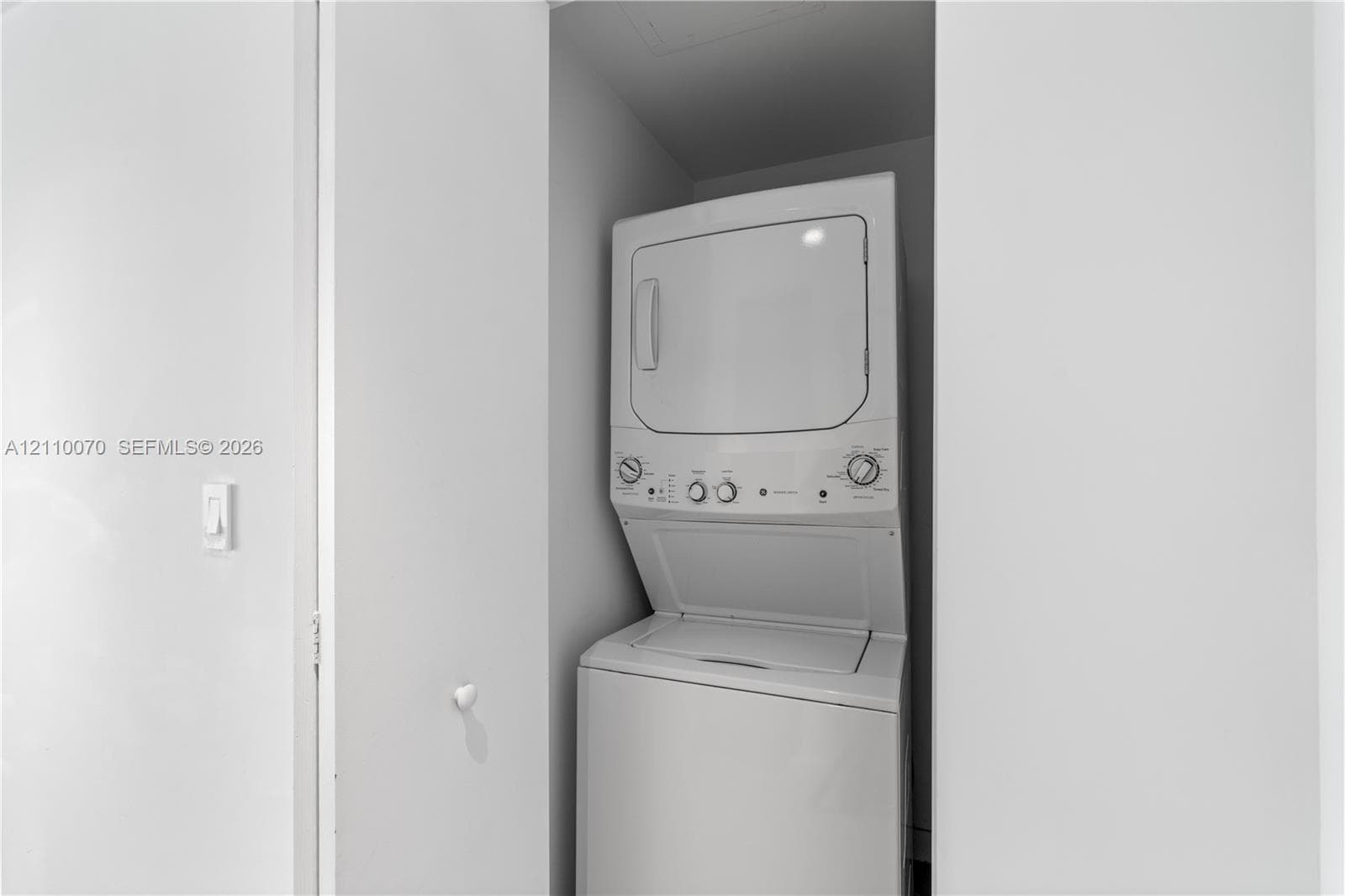 Built-in laundry closet featuring a white stacked washer and dryer unit