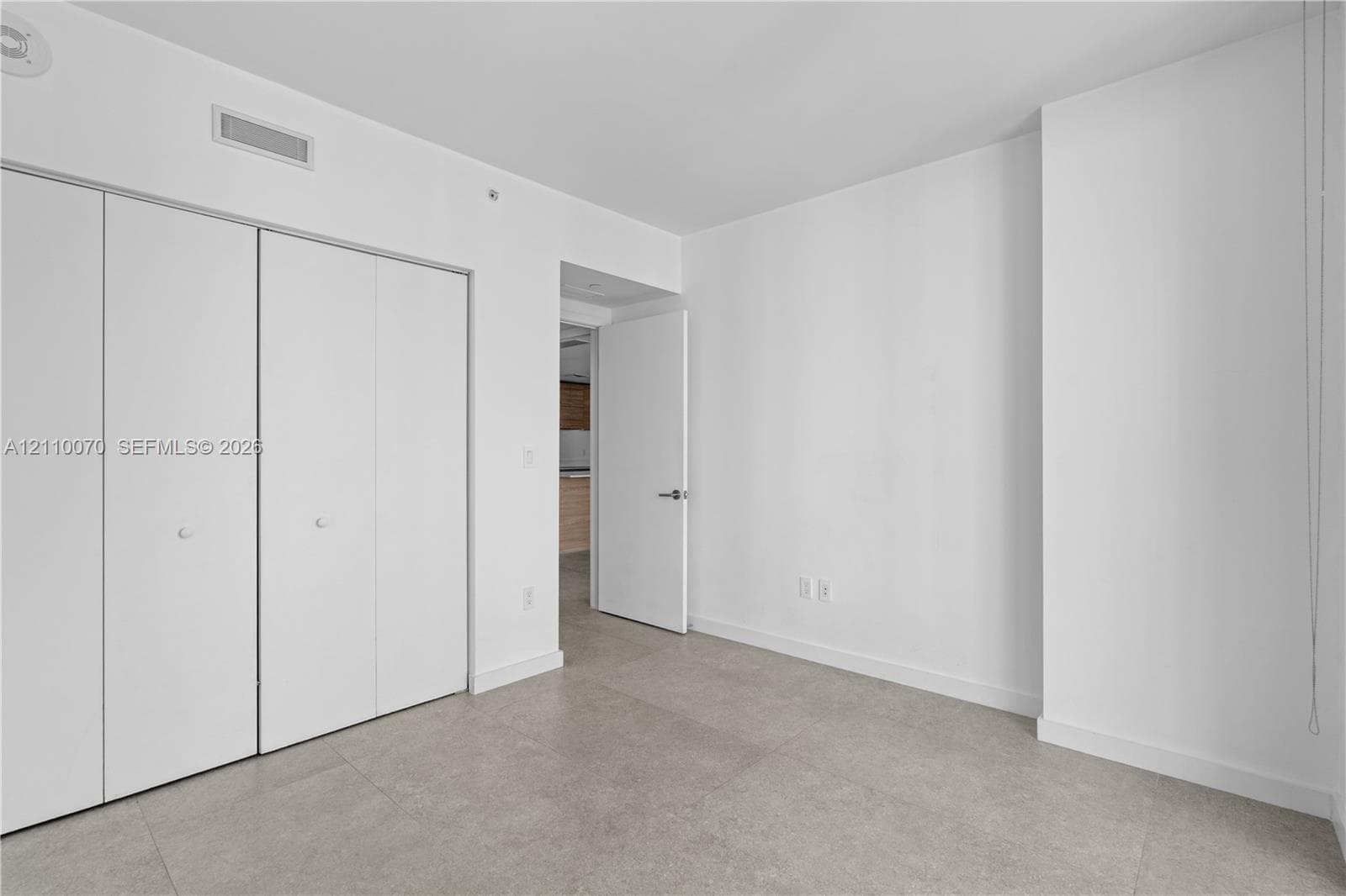 Room featuring large-format tile flooring, white walls, and built-in closet with four-panel folding doors