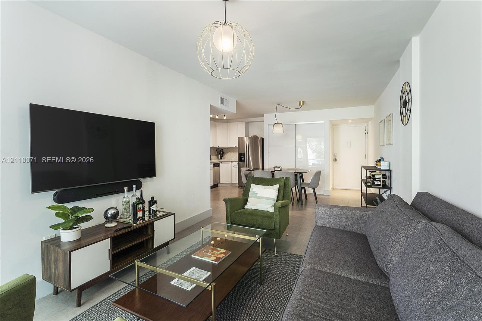 Open-concept interior featuring uniform light-toned flooring, spherical wire-frame pendant lighting, and crisp white walls