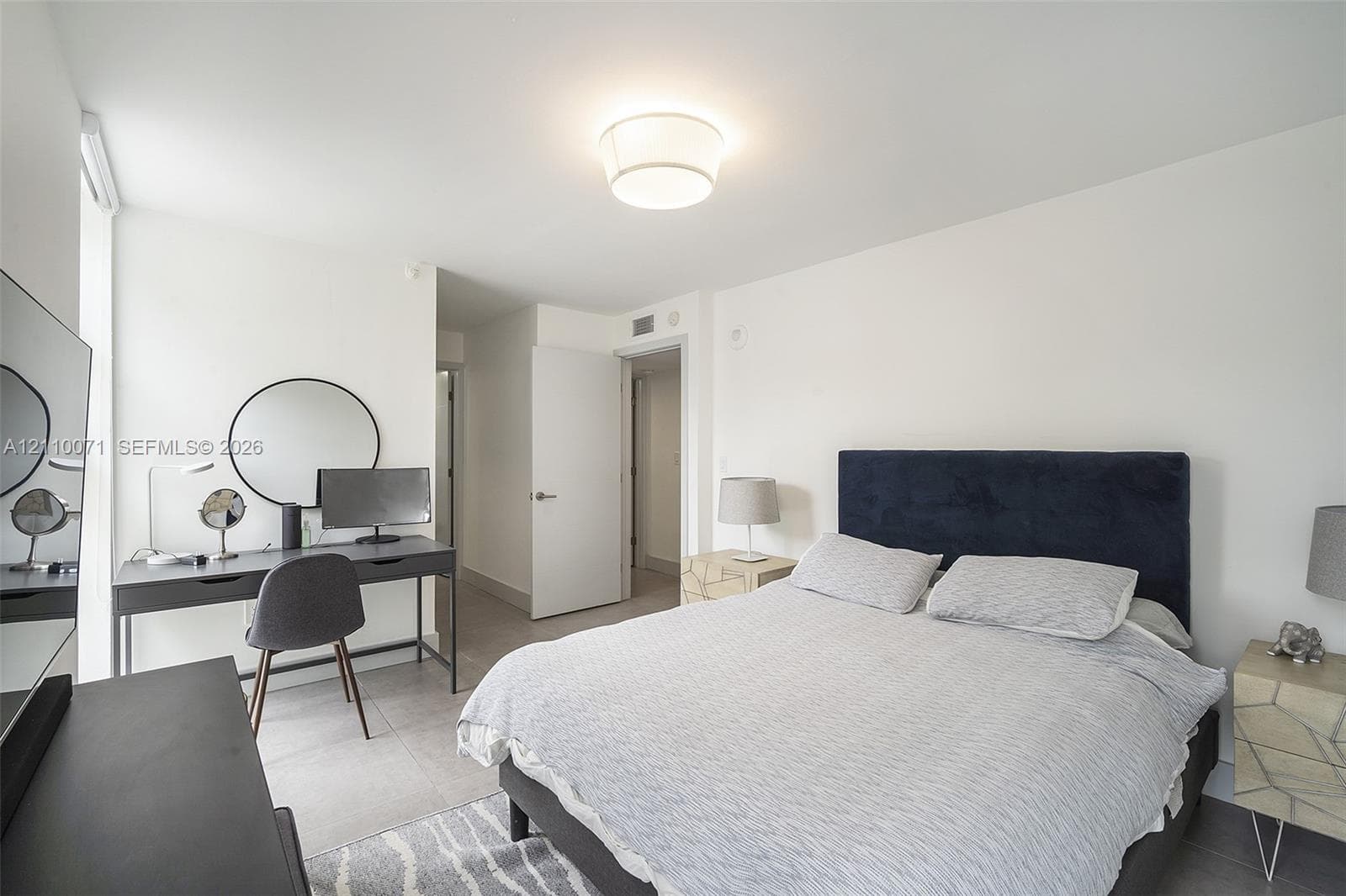 Neutral-toned interior featuring large-format ceramic floor tile, flush-mount drum ceiling light fixture, and solid-core interior doors