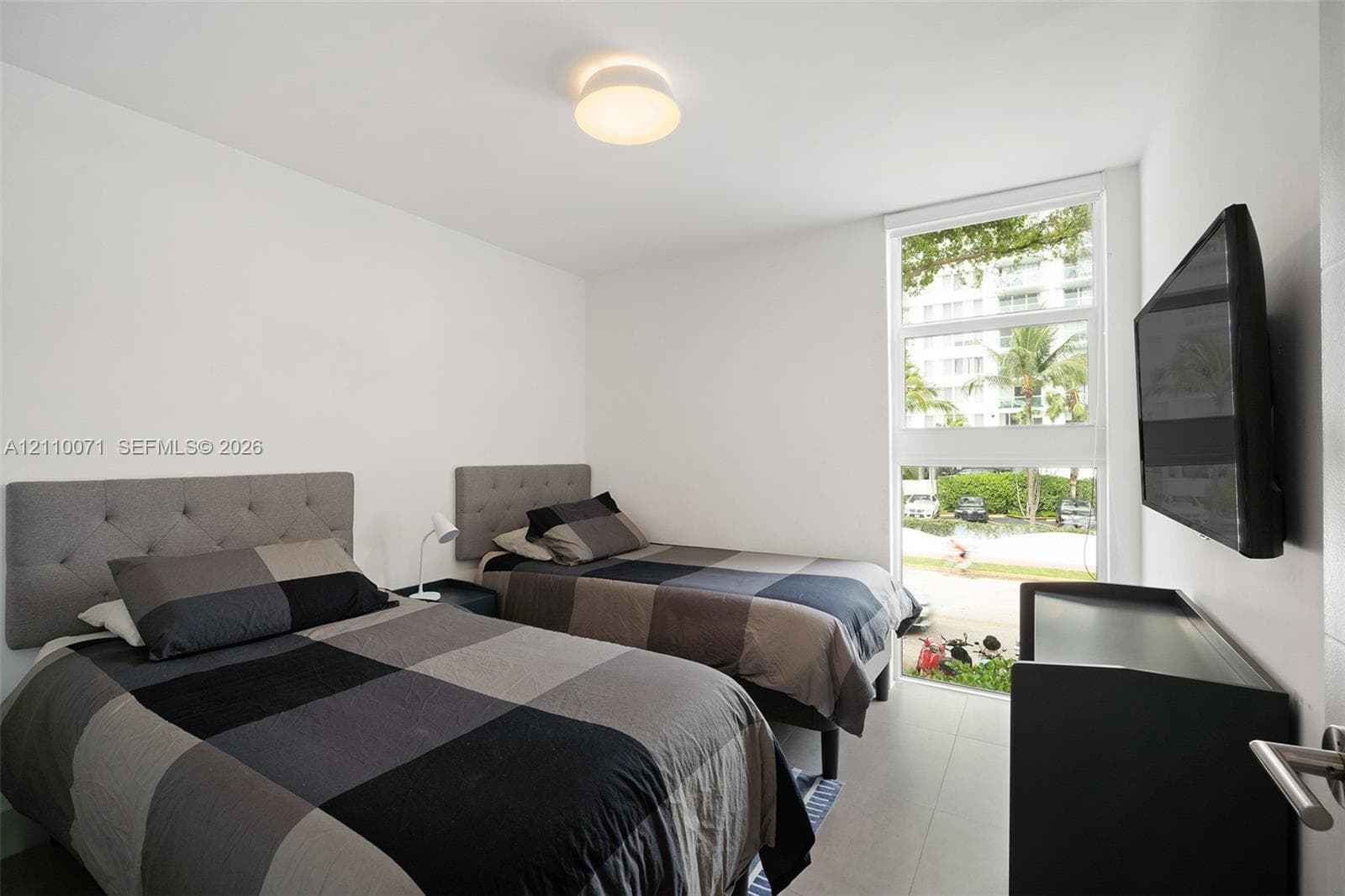 Minimalist room featuring large-format tile flooring, a floor-to-ceiling vertical window, and a flush-mount dome light fixture