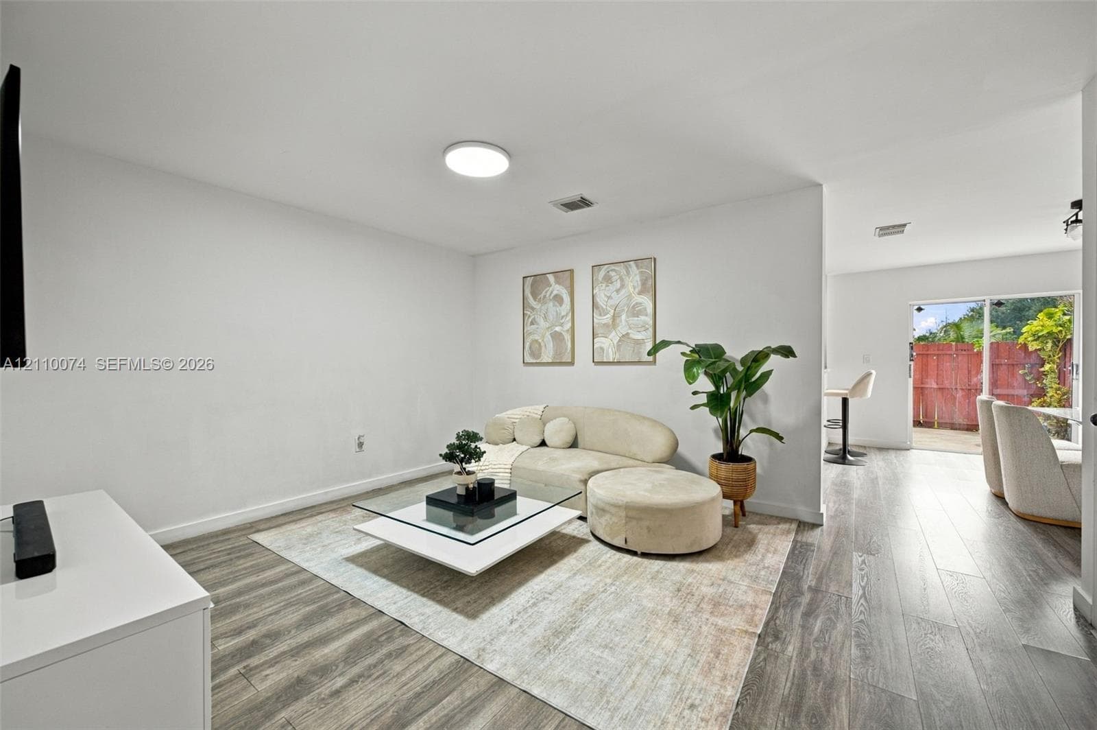 Neutral-toned interior featuring wood-finish flooring, recessed lighting, and a glass sliding door providing outdoor access