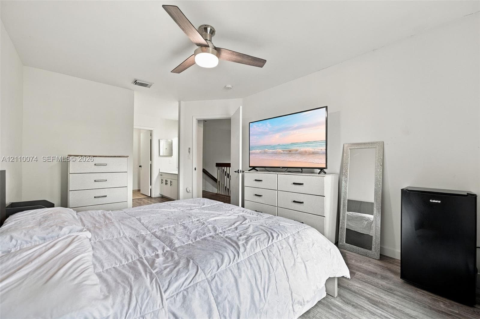 Wood-finish flooring and a central ceiling fan with an integrated light fixture