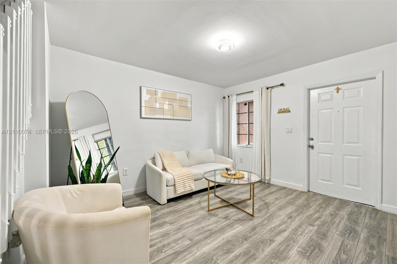 Neutral-toned interior space featuring wood-finish flooring, a six-panel entry door, and a multi-pane window with installed hardware