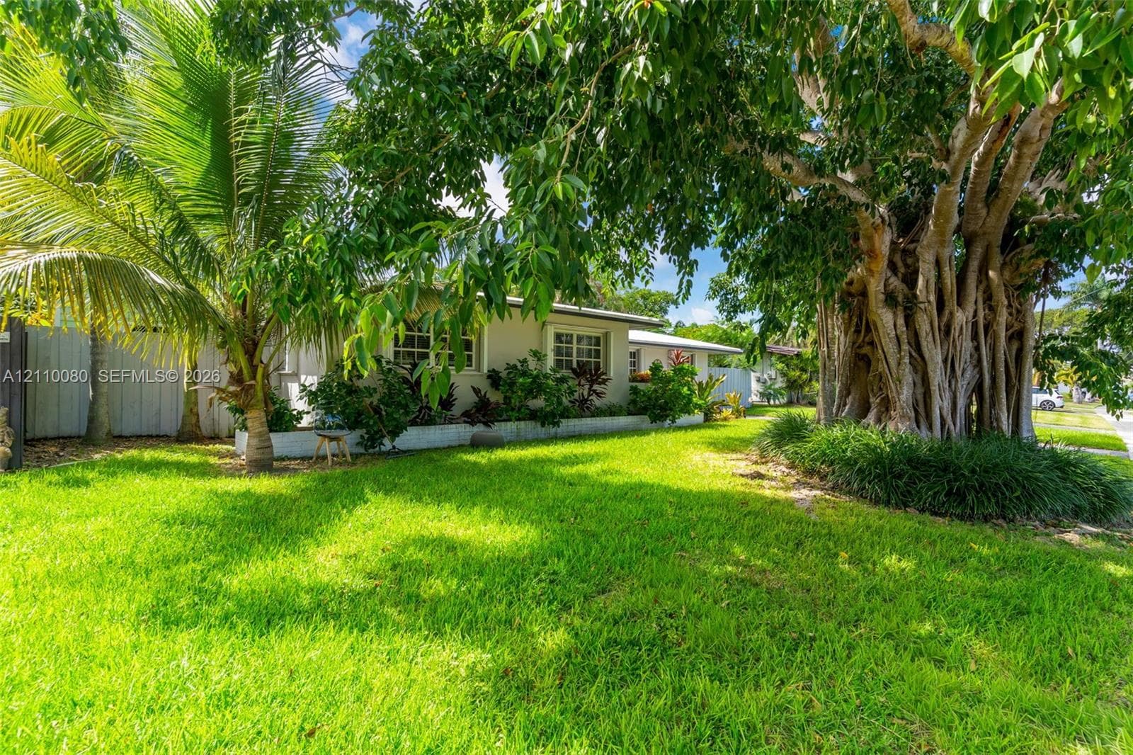 Exterior grounds featuring a manicured lawn, established landscaping, and mature canopy trees