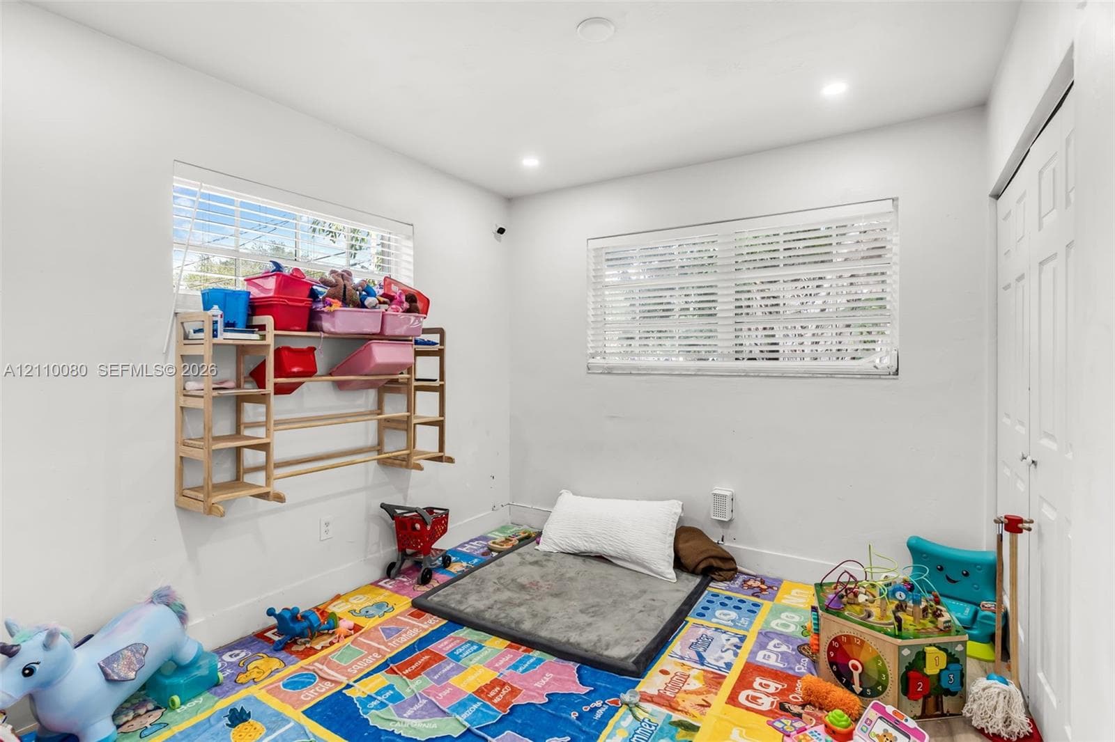 Room featuring neutral walls, recessed lighting, dual windows with horizontal blinds, and a closet with bifold doors