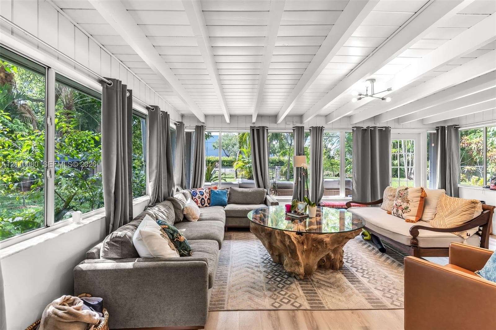 Sunroom featuring vaulted wood-beam ceilings, extensive paneled windows, and wood-finish flooring