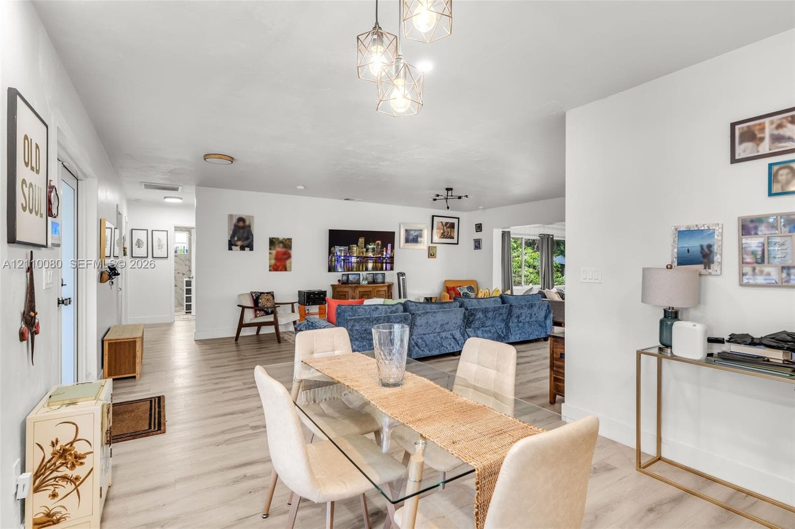 Open-concept interior featuring light-toned wood-finish flooring and geometric three-bulb pendant lighting
