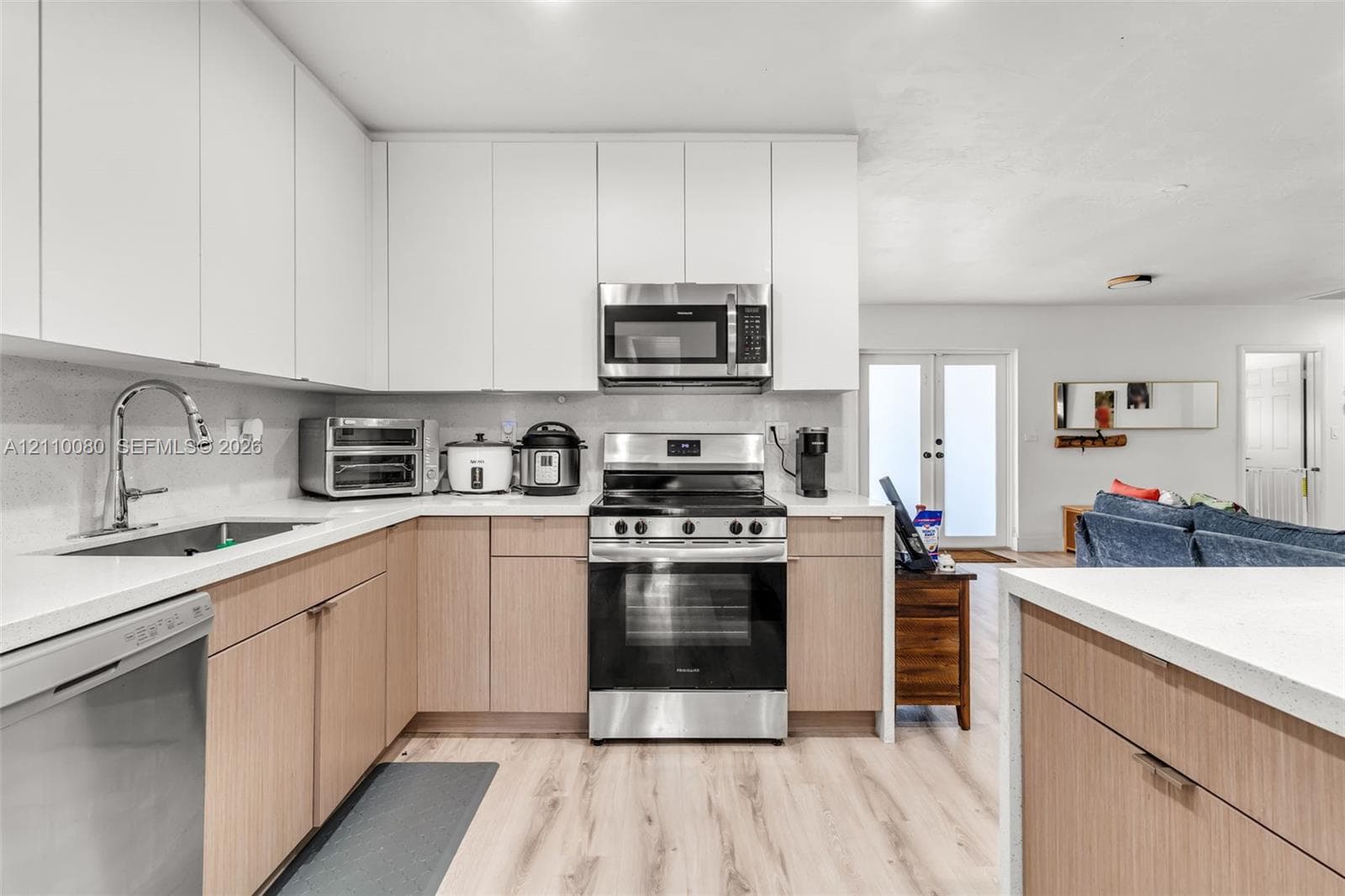 Kitchen featuring two-tone cabinetry, stone-finish countertops, stainless steel appliances, and wood-finish flooring