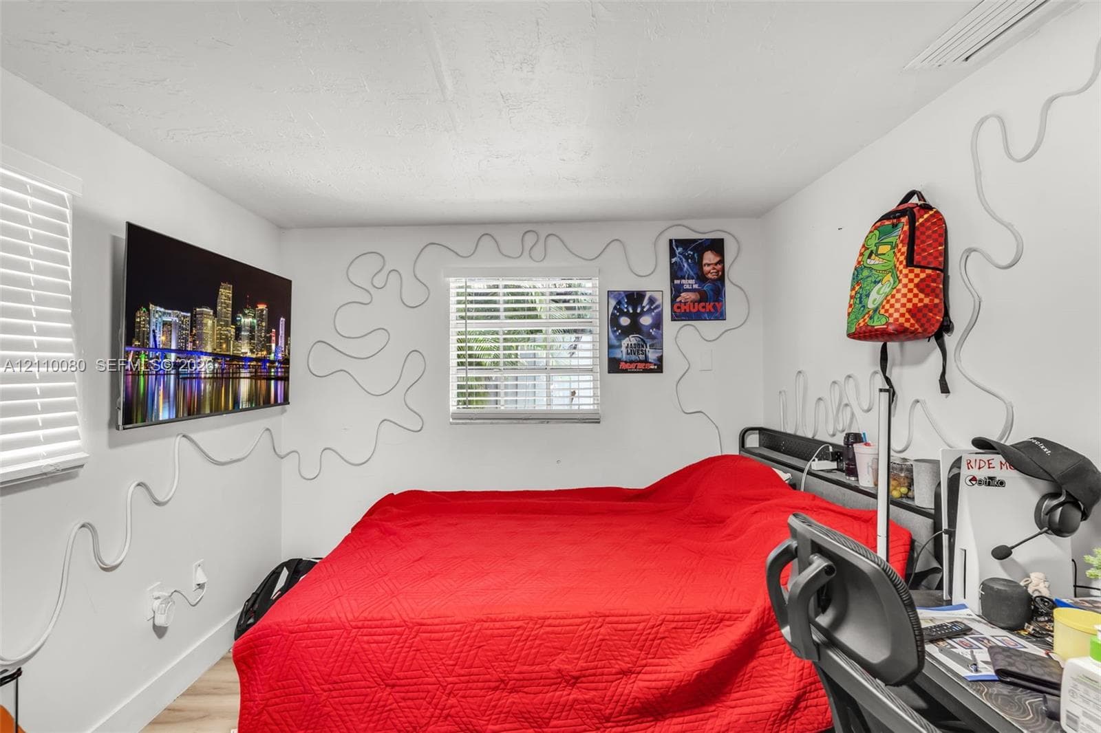 Bedroom featuring neutral wall paint, wood-finish flooring, and horizontal slat window blinds