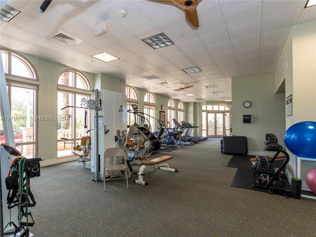 Fitness center featuring arched windows, paneled ceiling, recessed lighting, and integrated ceiling fans
