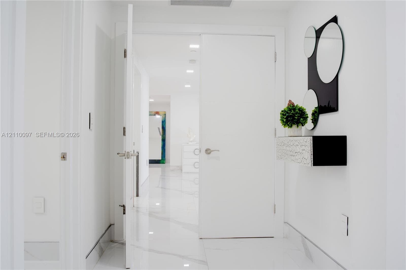 Interior hallway featuring large-format white veined flooring and recessed ceiling lighting