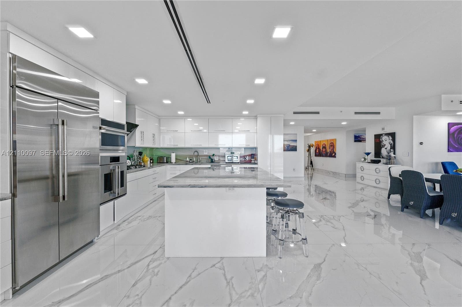 Contemporary kitchen featuring high-gloss cabinetry, a spacious central island with a stone countertop, large-format polished tile flooring, and integrated stainless steel appliances