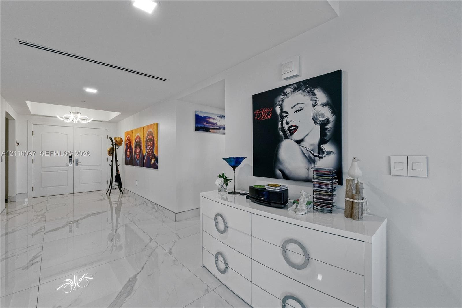 Foyer featuring high-gloss large-format tile flooring, double-door entry with arched panel detailing, recessed ceiling lighting, and a modern tiered chandelier