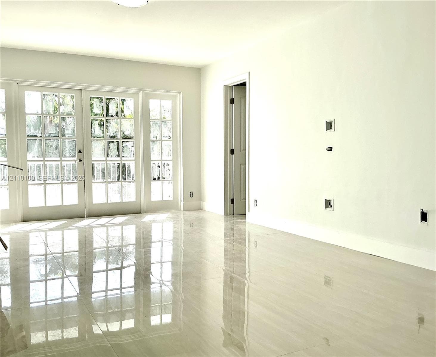 Polished neutral-tone tile flooring, multi-pane glass French doors, and smooth wall finish