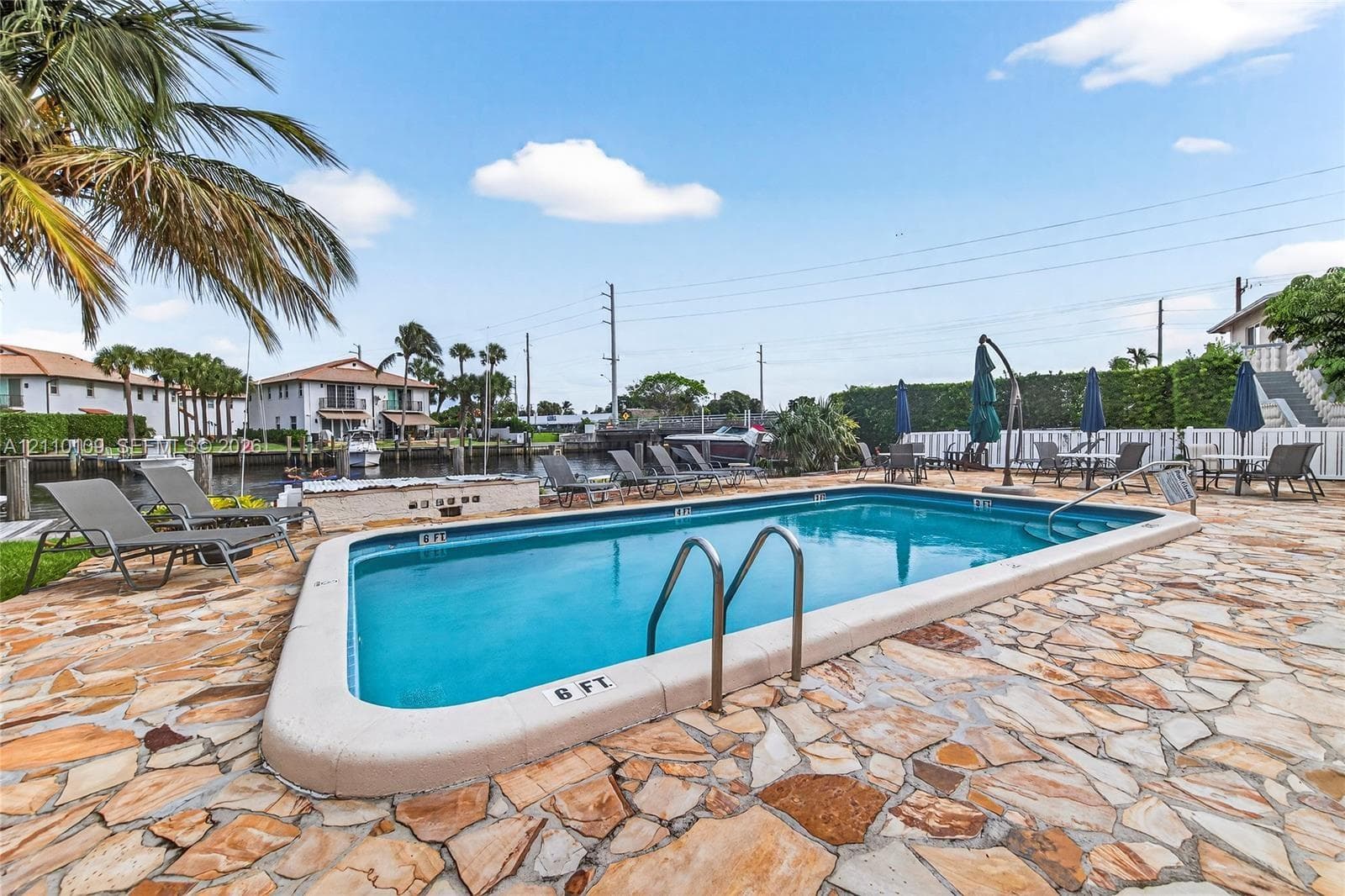In-ground swimming pool featuring a flagstone deck, integrated metal ladders, and bulkhead access to a canal