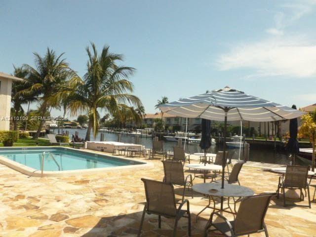 Waterfront patio featuring natural stone hardscaping, an in-ground swimming pool, and direct canal access