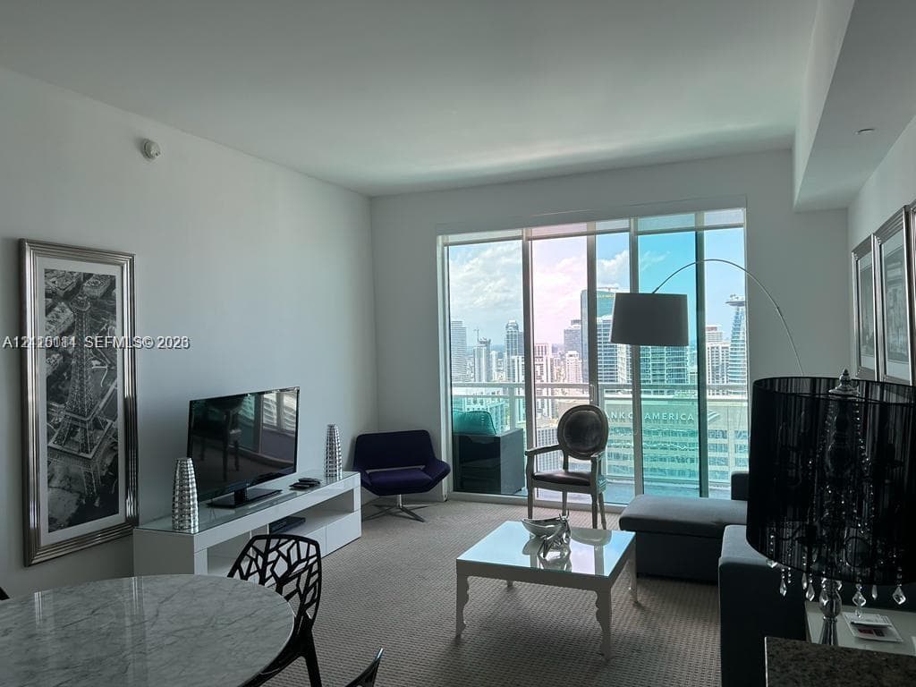 Floor-to-ceiling glass windows, private balcony, and neutral carpeting