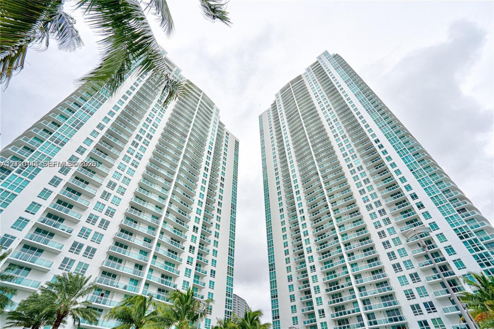 High-rise residential towers featuring expansive floor-to-ceiling windows, uniform private balconies, and glass facade detailing