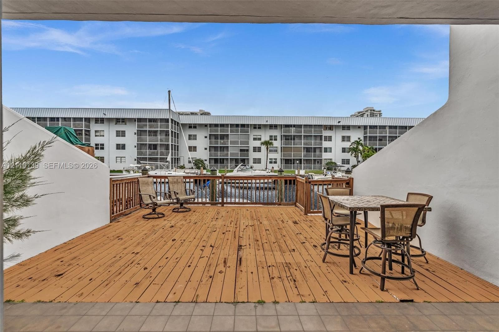 Covered exterior deck with wood-finish decking and perimeter wood railing, situated over water