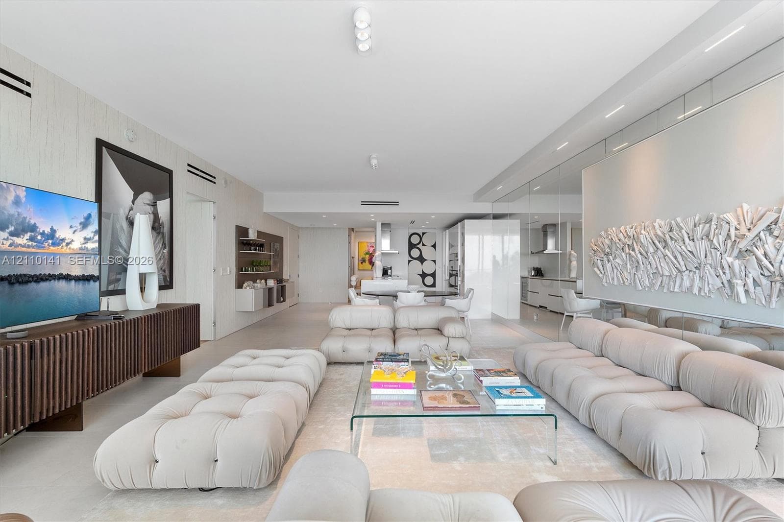 Open-concept interior featuring smooth solid-surface flooring, full-wall mirrored accents, recessed ceiling lighting, and custom linear built-in cabinetry