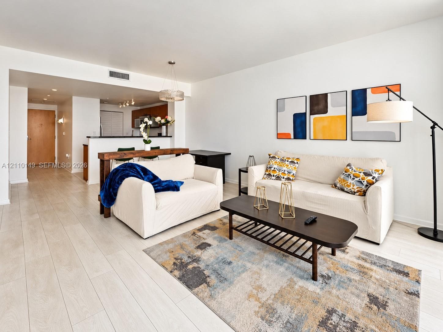 Open-concept interior featuring light-toned wood-finish flooring, recessed lighting, and a breakfast bar with wood-surfaced counter