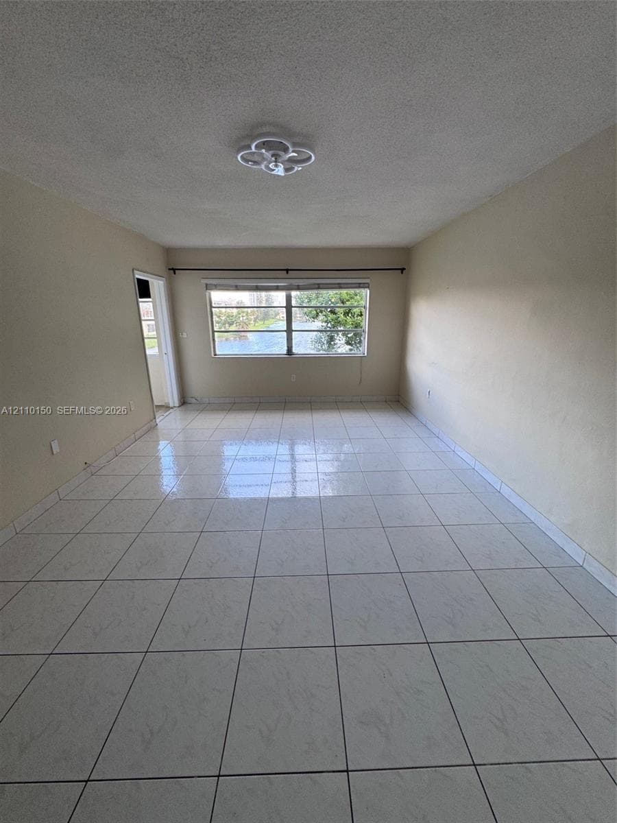 Neutral-toned interior space featuring light-colored square tile flooring and a ceiling-mounted flush light fixture