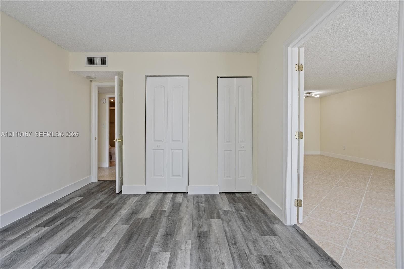Interior space featuring gray wood-finish flooring, dual bi-fold closet doors, and neutral wall tones