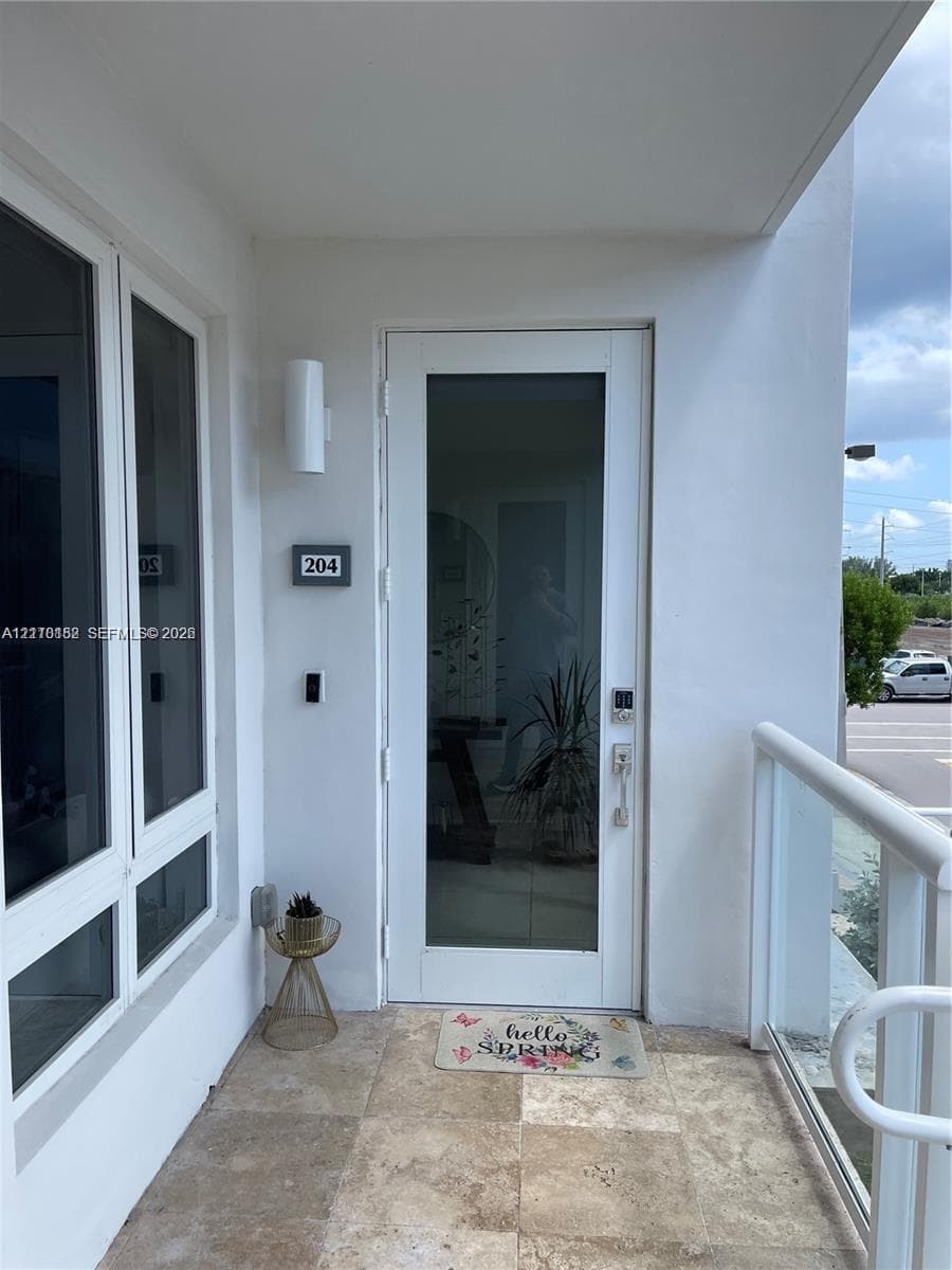Entryway featuring a full-length glass-panel door, natural stone flooring, and a glass-paneled railing