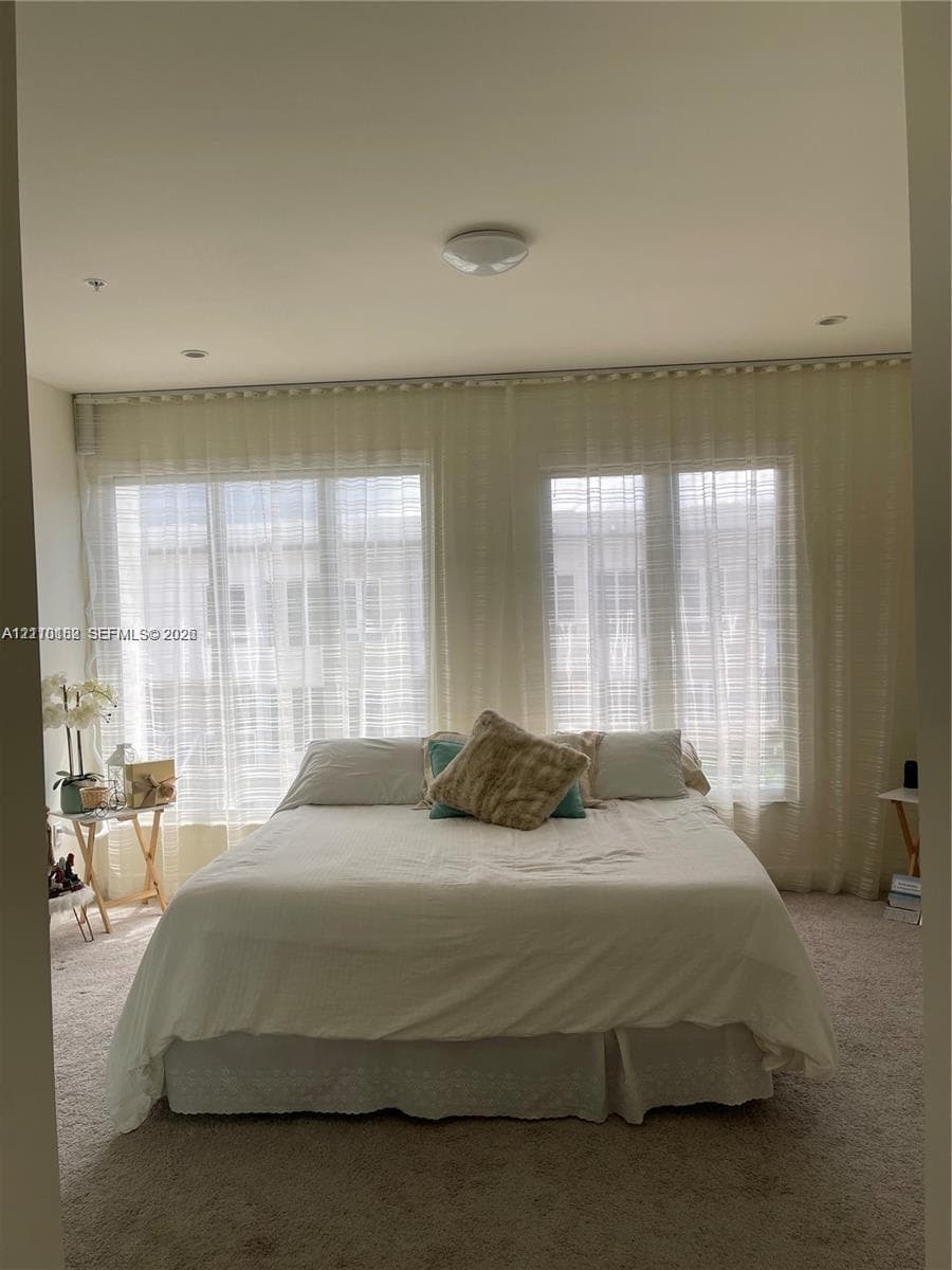 Expansive windows featuring floor-to-ceiling sheer drapery, plush carpeting, and recessed ceiling lighting