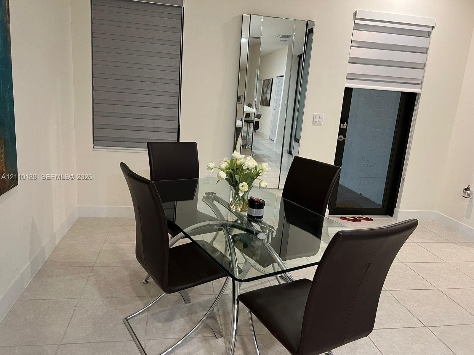 Neutral-toned floor tiles, floor-to-ceiling wall mirror, and dual-layered window treatments
