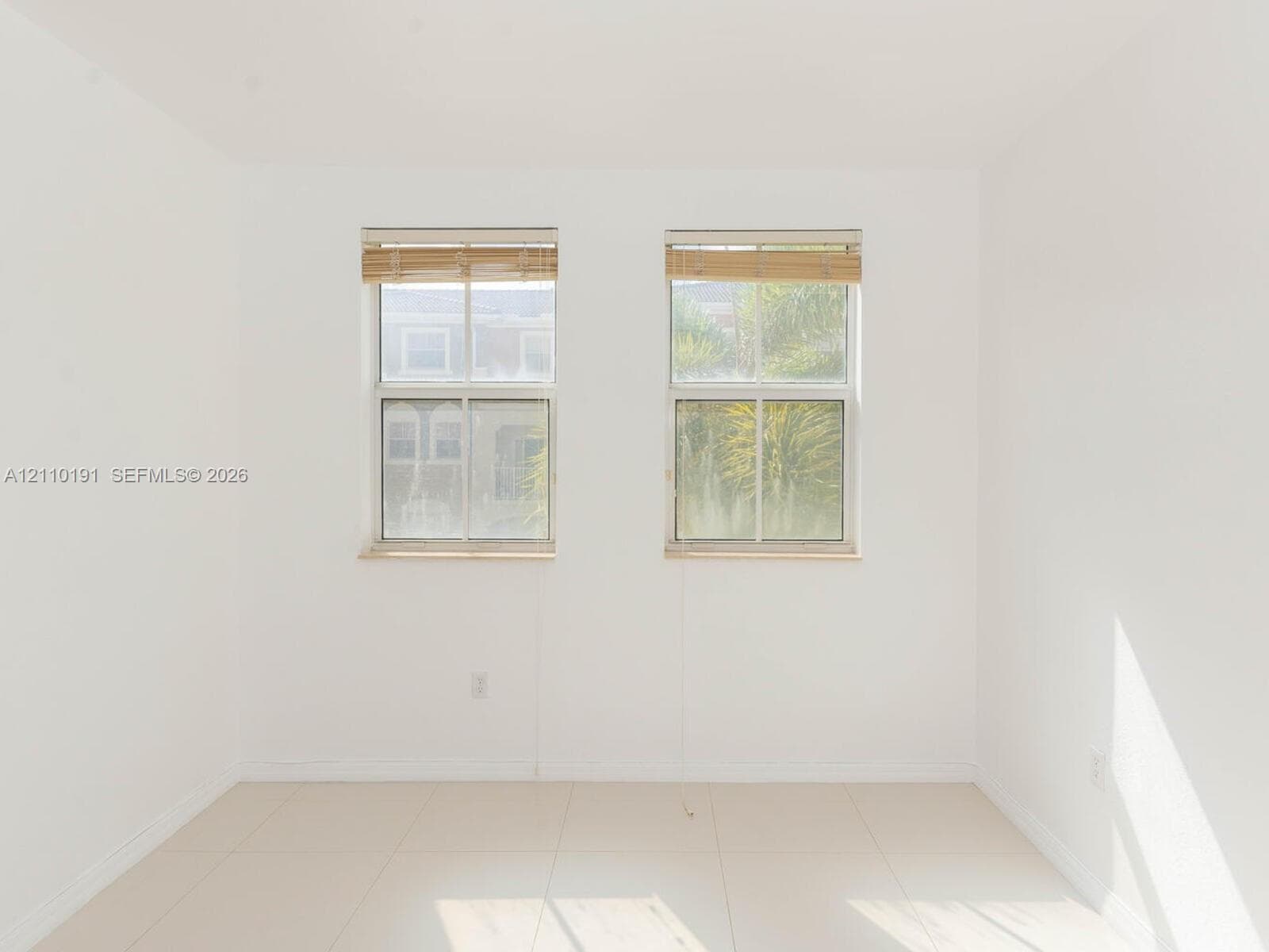 Neutral-toned walls paired with large-format floor tile, complemented by two double-hung windows featuring wood-finish blinds