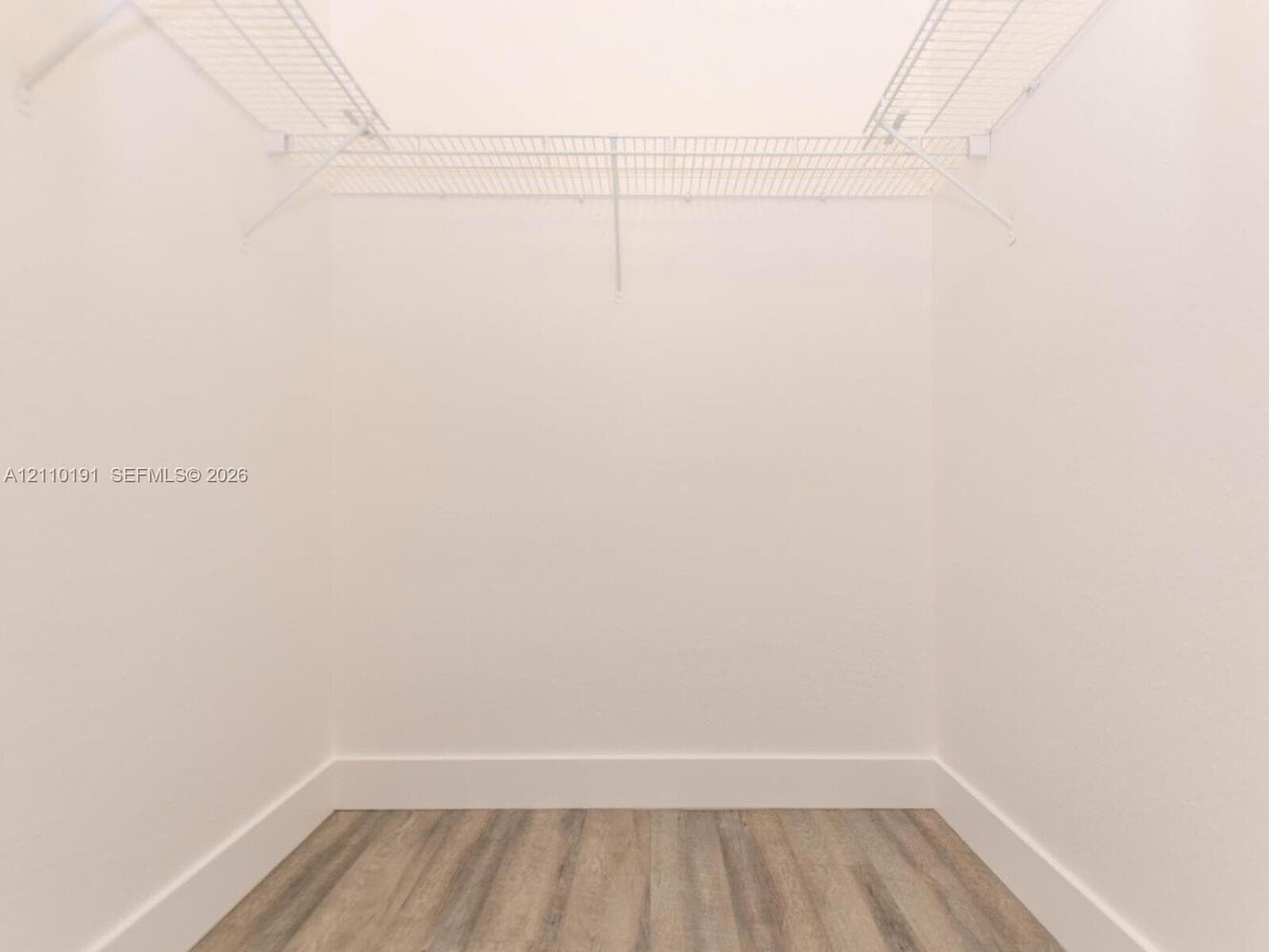 Walk-in closet featuring white wire shelving and wood-finish flooring